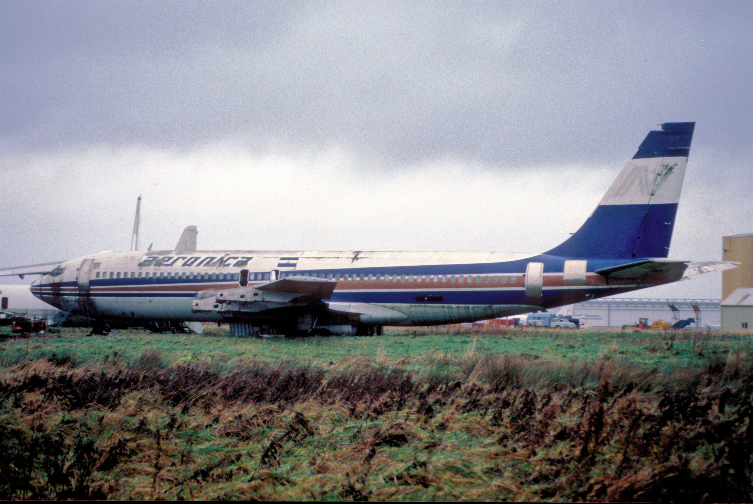 Avión Aeronica Boeing 707-123B envejecido en un campo verde en un día nublado. Por el usuario Aero Icarus en Flickr. Usado bajo licencia CC BY-SA 2.0.